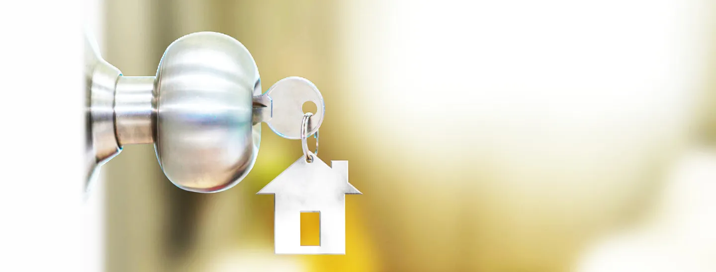 House shaped keychain and key unlocking a door