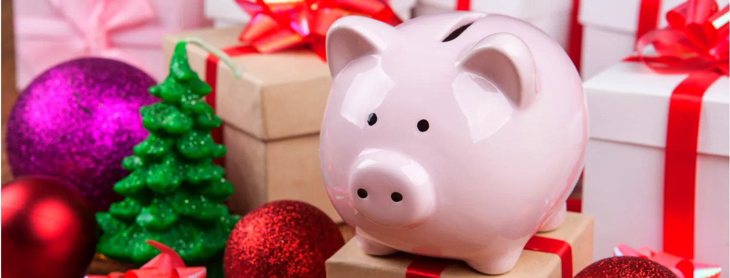 Pink piggy bank on a gift box with Christmas decorations 