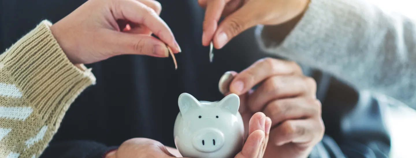FECU members inserting coins into a piggy bank.