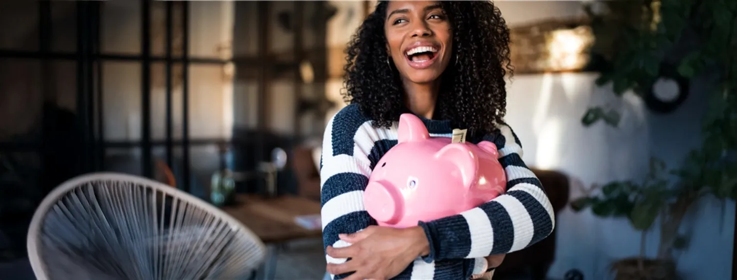 Woman smiling and holding a piggy bank