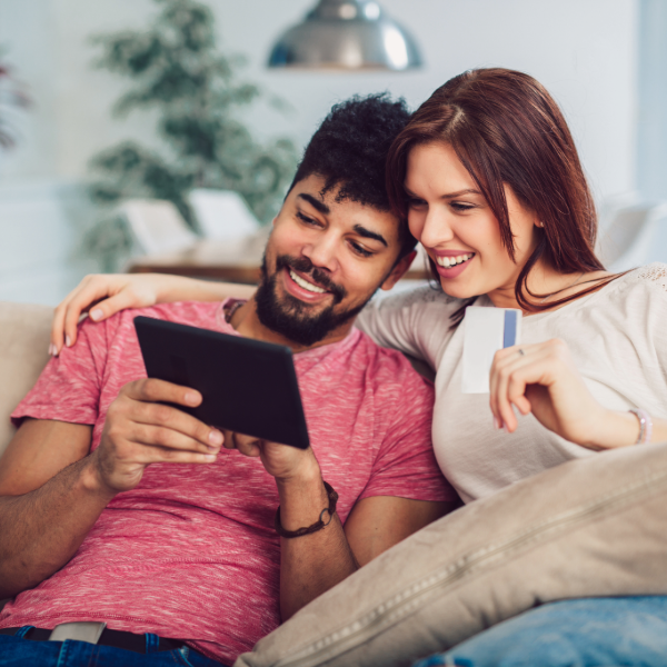 A couple sitting at home using a tablet to view online announcements   